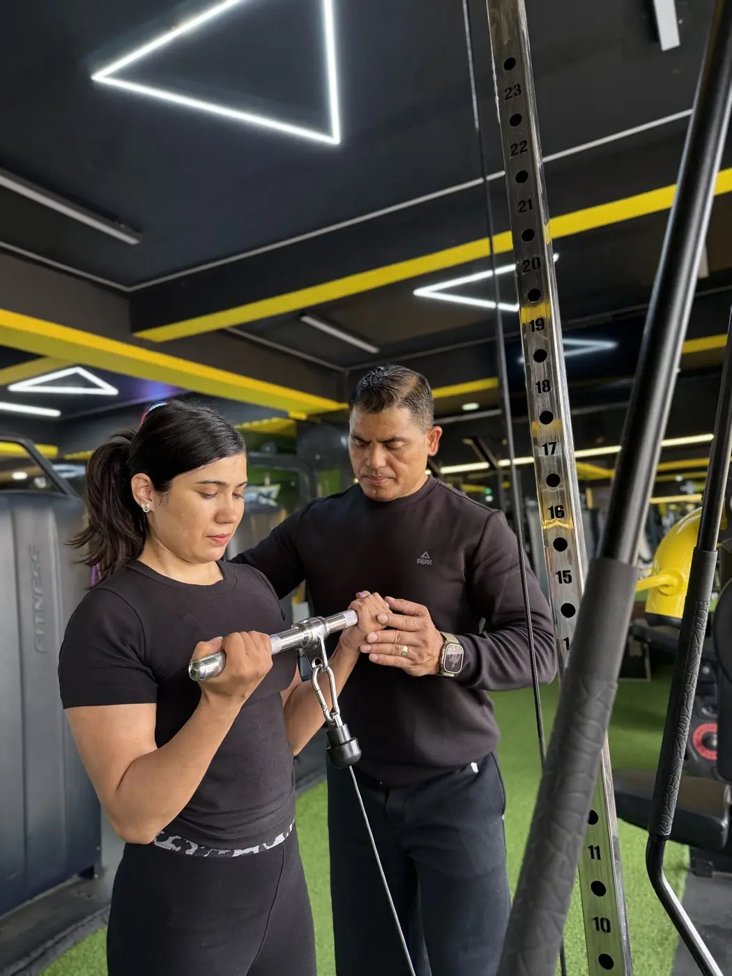 Coach adjusting a member’s grip on a cable bar