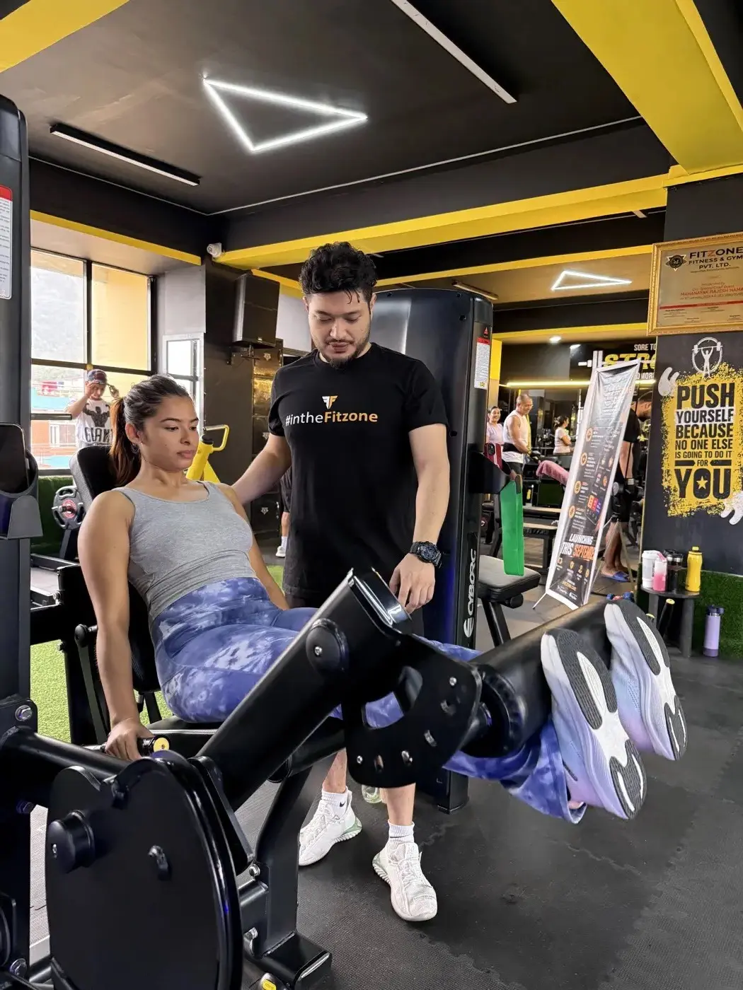 Coach spotting a member on a leg press
