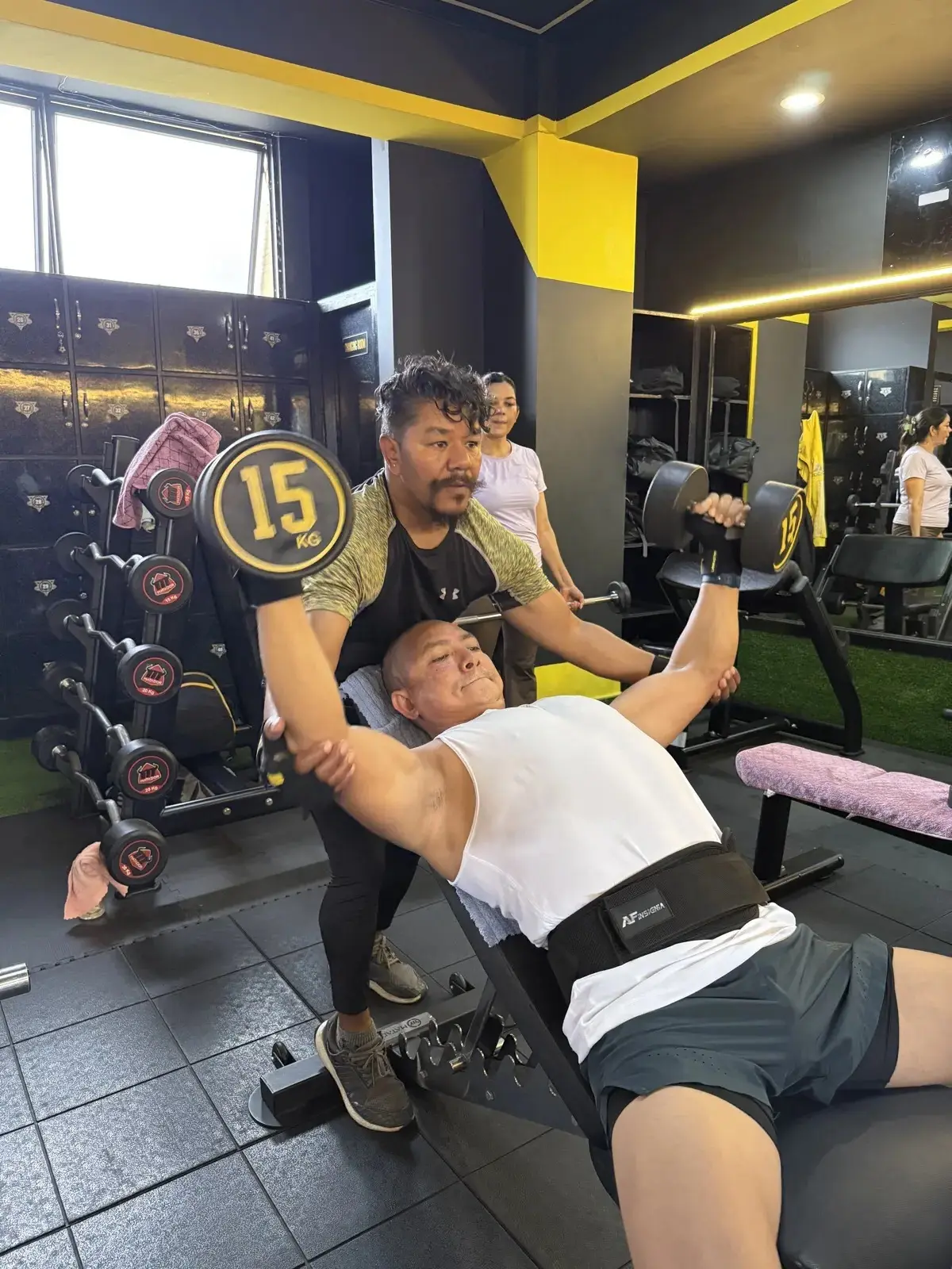 Coach spotting a member through an incline dumbbell press